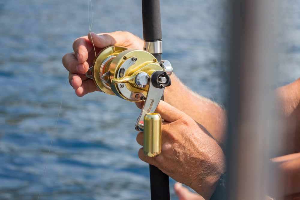 person holding gold fishing reel